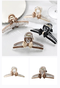 Détail de grandes pinces à cheveux en acrylique avec nœud en plusieurs couleurs terreuses