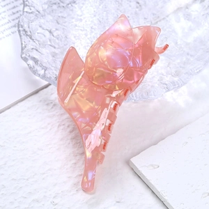 Pince à cheveux tulipe rose en acétate nacré posée sur un magazine esthétique