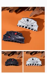 Detail of Halloween spider web hair claw clips in red and black on a festive orange background