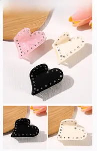 Detail of heart-shaped acetate hair claws with sparkling rhinestones in pink, beige, and black