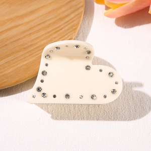 Elegant cream acetate heart hair claw with rhinestones on a minimalist white background