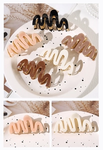 Detailed close-up of wavy acetate hair claws with premium gold metallic trim accents