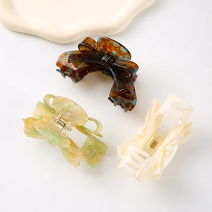 Three elegant acetate bow hair claws in tortoiseshell, light green marble and cream white