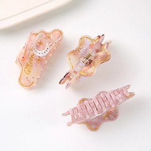 Pink marble acetate hair claw clip with gold moon star patterns and sparkling rhinestones