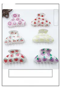 Detail view of large hair claw clips featuring colorful printed summer fruit patterns