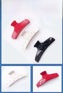 Detail view of acetate hair claws in red, white and black with colorful rhinestones