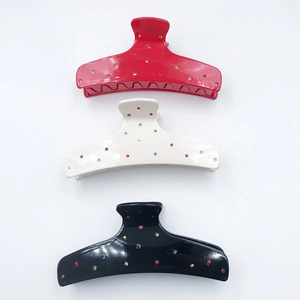 Three-piece acetate shark hair claws in red, cream, and black with colorful rhinestones
