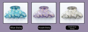 Close-up of glitter acrylic hair claws with white daisy prints in blue, purple and gold