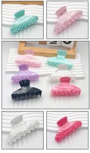Detail showing the marbled texture of six colorful acrylic hair claw clips on white stands