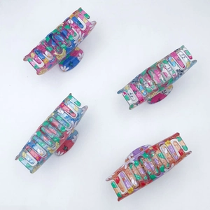Set of four floral printed PVC hair claws with colorful daisy patterns in a matte finish