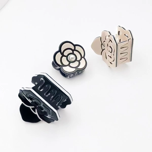 Three elegant acrylic camellia hair claws with pearl accents and hollow rose designs
