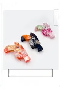 Detail of three large parrot-shaped cellulose acetate hair clips in marble patterns