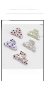 Detailed view of five large PVC hair claws with strawberry, cherry, and floral prints