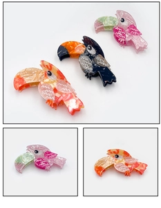 Detail of toucan-shaped acetate hair claws in pink, black, and orange finishes