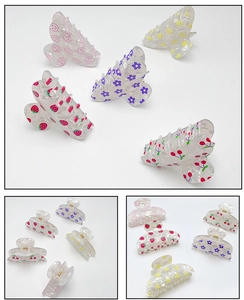 Close-up of transparent acrylic hair claws with strawberry and cherry fruit patterns