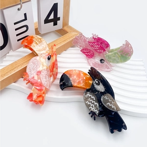Three elegant toucan shaped acetate hair claws in various marble textures and colors