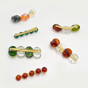 Variety of irregular amber resin hair clips with golden metal base on white background