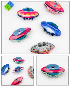 Detail showing colorful acrylic UFO hair claws with cute cartoon alien prints and glossy finish