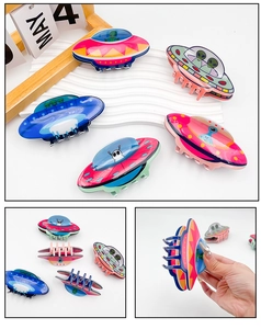 Close-up of colorful PVC alien and UFO hair claws showing detailed cartoon print and grip
