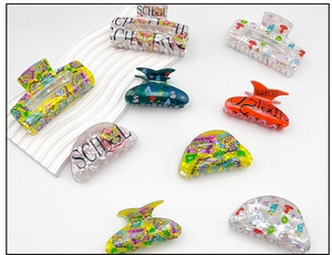 Detail of square and semi-circular acrylic hair claws with glitter and school-themed prints