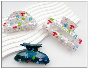 Detail of acrylic hair claws with colorful letter prints on a white decorative tray