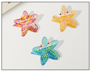Close-up of three starfish hair claws in pink, yellow and blue colors with playful dots