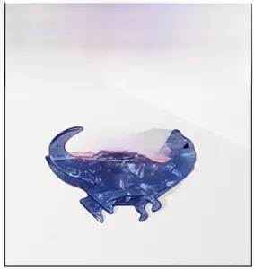 Detailed close-up of a blue dinosaur hair claw clip with pink back fin accents