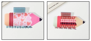 Detail view of two creative pencil-shaped hair claws with heart patterns and XOXO prints