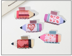 Detail showing five pencil-shaped Valentine's Day hair claws with heart patterns and love text