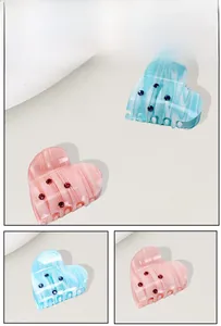 Macro detail of heart-shaped hair claws with marble texture and small rhinestones
