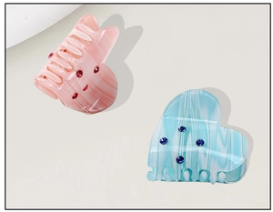 Detail of pink and blue marbled heart hair claws with sparkling rhinestone accents