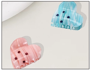 Close-up of pink and blue acetate heart hair claws with shimmering rhinestones detail