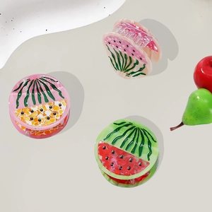 Three acetate watermelon hair claws in pink, orange, and green with a jelly texture finish