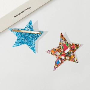 Sparkly star hair clips with Christmas prints and sequins on a light background