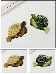 Détail de pinces à cheveux en forme de tortue en acétate aux textures jaune et verte