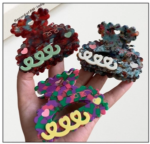 Detailed macro view of heart-shaped acetate hair claws in multiple floral patterns