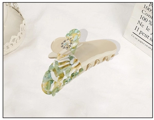 Close-up of acetate flower claw clip with colorful marble pattern and rhinestones