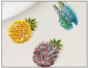Three acetate pineapple claw clips in yellow, blue, and pink marble with pink rhinestones