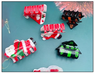 Close-up of festive acrylic hair claws featuring Santa Claus and Christmas themed patterns