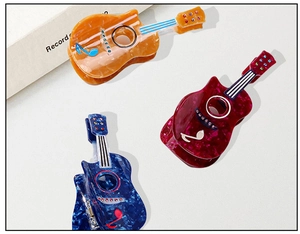 Detail view of guitar shaped hair claws with marble texture and rhinestone accents
