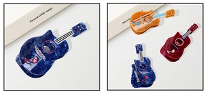 Detail view of guitar-shaped acetate hair claws with marble texture and rhinestones