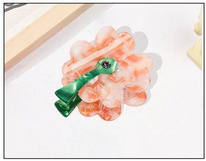 Detail of peach pink acetate flower hair claw clip with green stem and rhinestone inlay