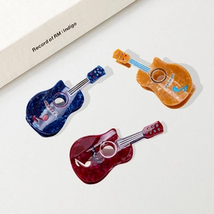 Guitar-shaped acetate hair claws set in blue, brown, and red with rhinestone accents