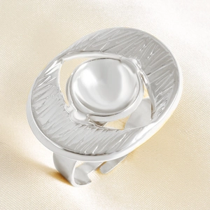 Macro detail of irregular silver ring with 3D texture and central sphere on silk