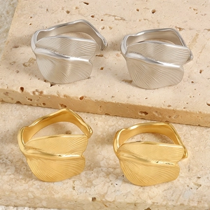Macro detail of leaf-shaped rings in gold and silver finish on stone background