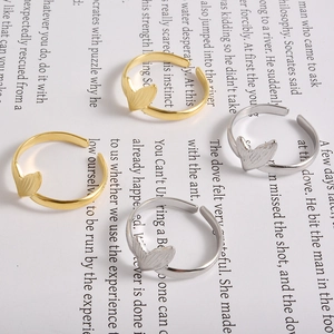 Flat lay of artistic gold and silver fishtail open rings on vintage book pages