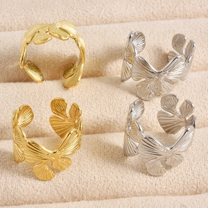 Detail of adjustable ginkgo leaf rings in gold and silver finish on a velvet tray