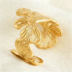 Close-up of golden stainless steel ginkgo leaf open ring on beige silk background
