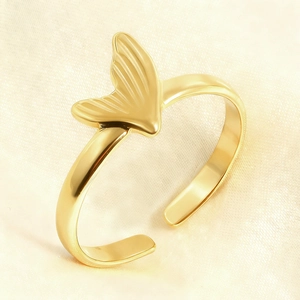 Macro shot of gold-plated fish tail ring showing fine texture on cream silk fabric