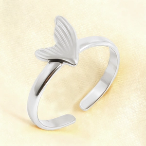 Detailed close-up of a silver fishtail open ring on soft yellow satin background
